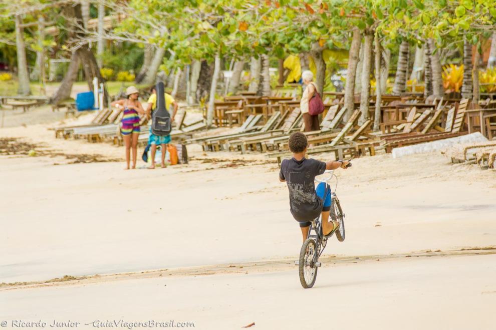 Imagem de um menino andando de bicicleta nas areias da Praia do Espelho.